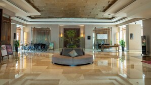 A spacious lobby with a central seating area, a ceiling with recessed lighting, and a polished floor.