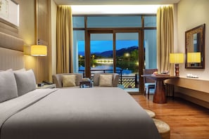 Habitación de hotel con una cama grande, un escritorio, una silla y vista a un puente sobre el agua.