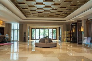 Una hall con un’area salotto circolare, una reception e ampie finestre.