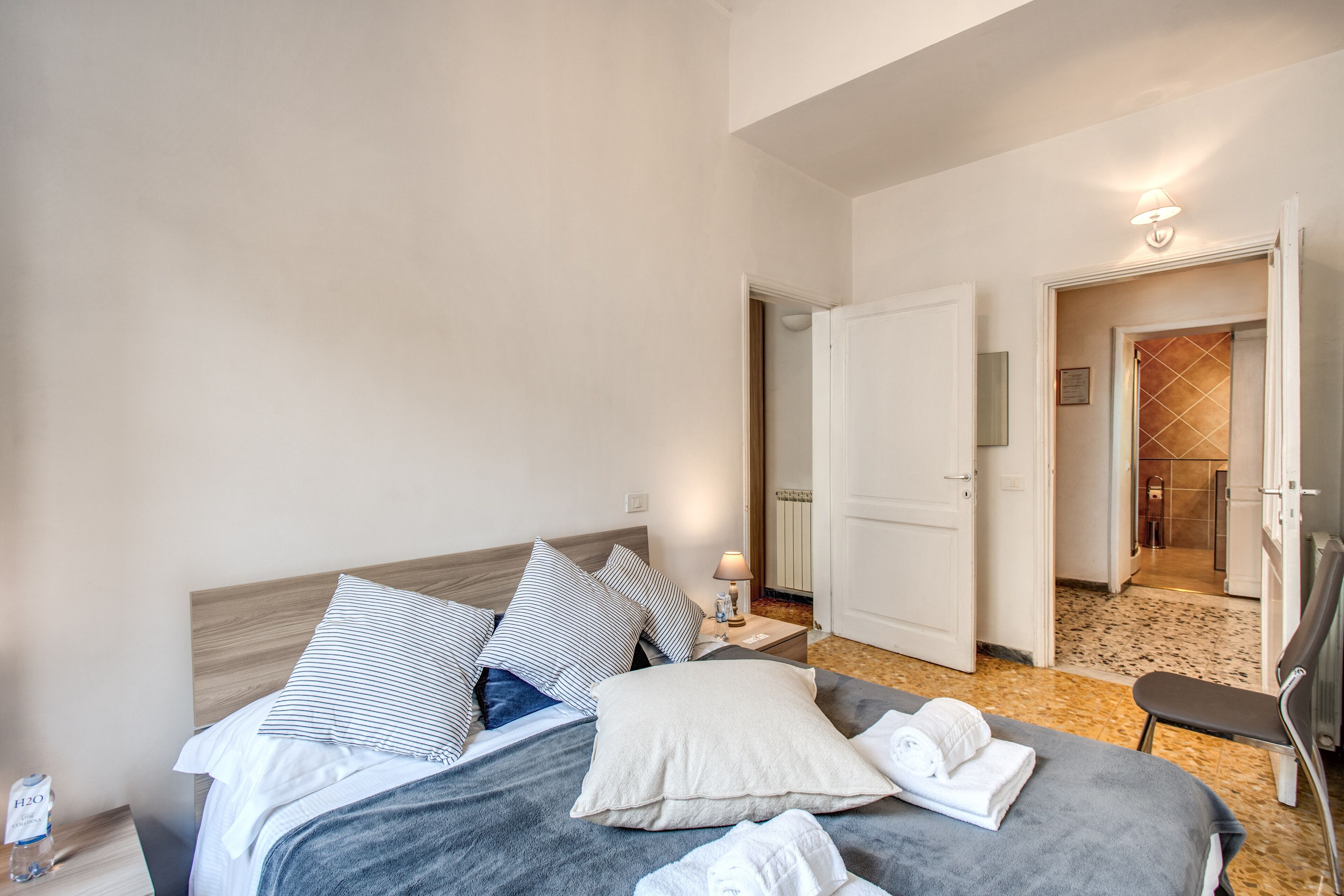 Une chambre d’hôtel comprenant un lit, des oreillers, une table de chevet avec une lampe et une chaise.