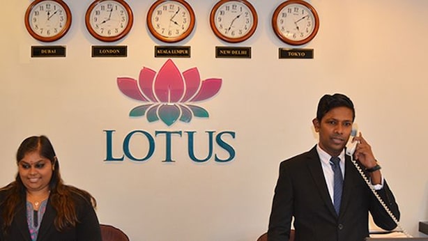 A reception desk with clocks indicating different time zones and a lotus logo. - Lotus Hotel KL Sentral (Kuala Lumpur)