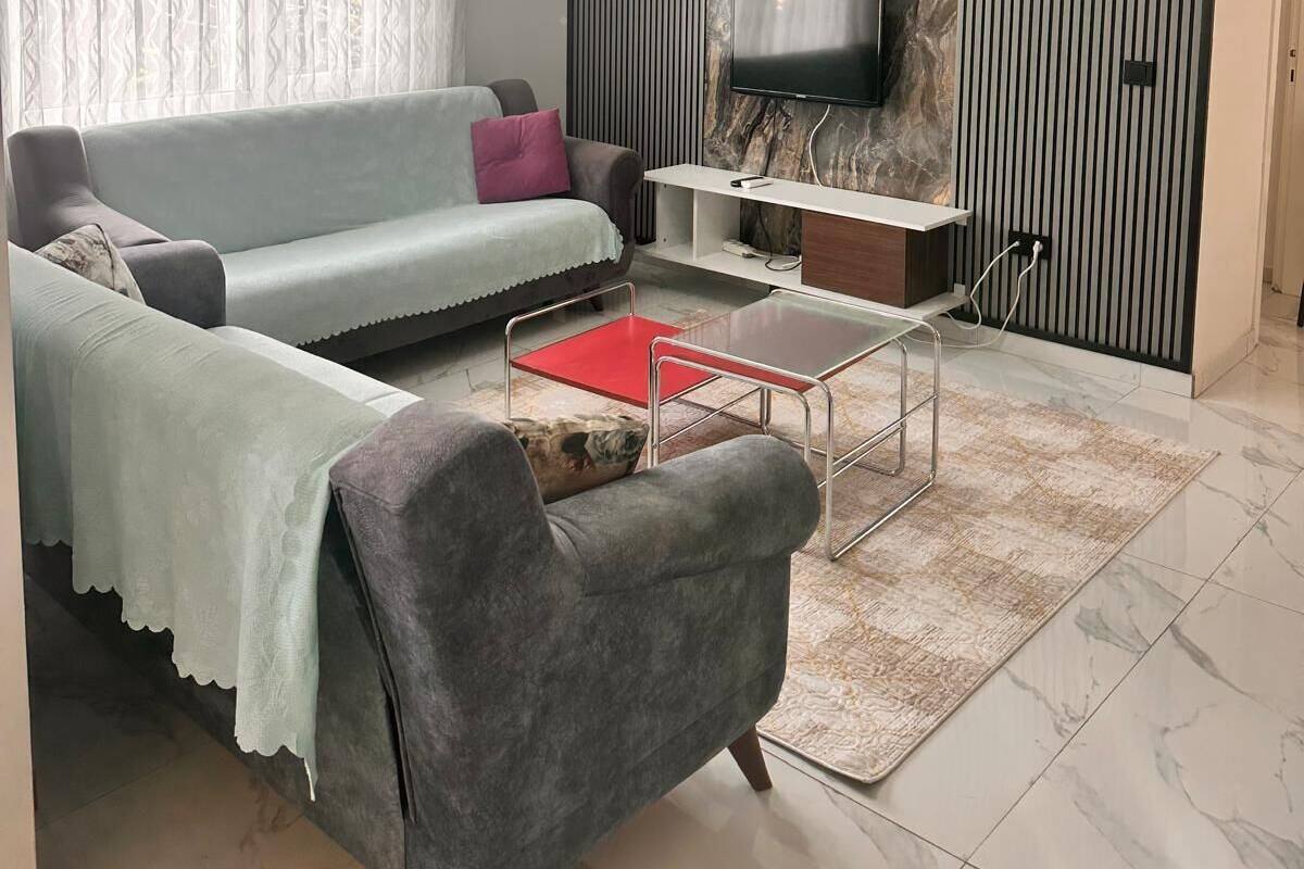 Ein modernes Wohnzimmer mit einer Couch, einem Couchtisch, einem Fernseher und einer Wand mit Muster.