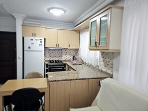 Une cuisine compacte avec des meubles en bois, une cuisinière intégrée et un petit coin repas.