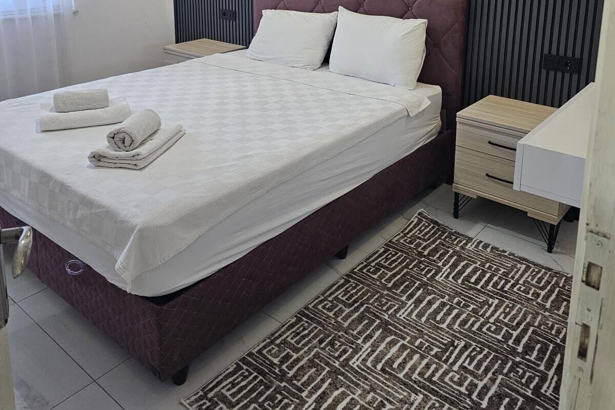 Ein modernes Schlafzimmer mit einem großen Bett, einer Marmorwand und einem gemusterten Teppich.