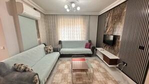 Ein modernes Wohnzimmer mit einer Couch, einem Couchtisch, einem Fernseher und einer Wand mit Muster.