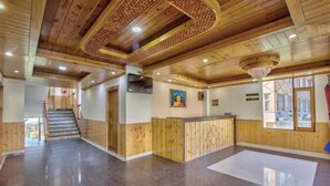 A spacious lobby with wooden paneling, a reception desk, and a staircase leading to upper floors. - Hotel Wild Rose (Manali)