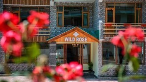 A building with a sign reading "WILD ROSE" and a stone facade. - Hotel Wild Rose (Manali)