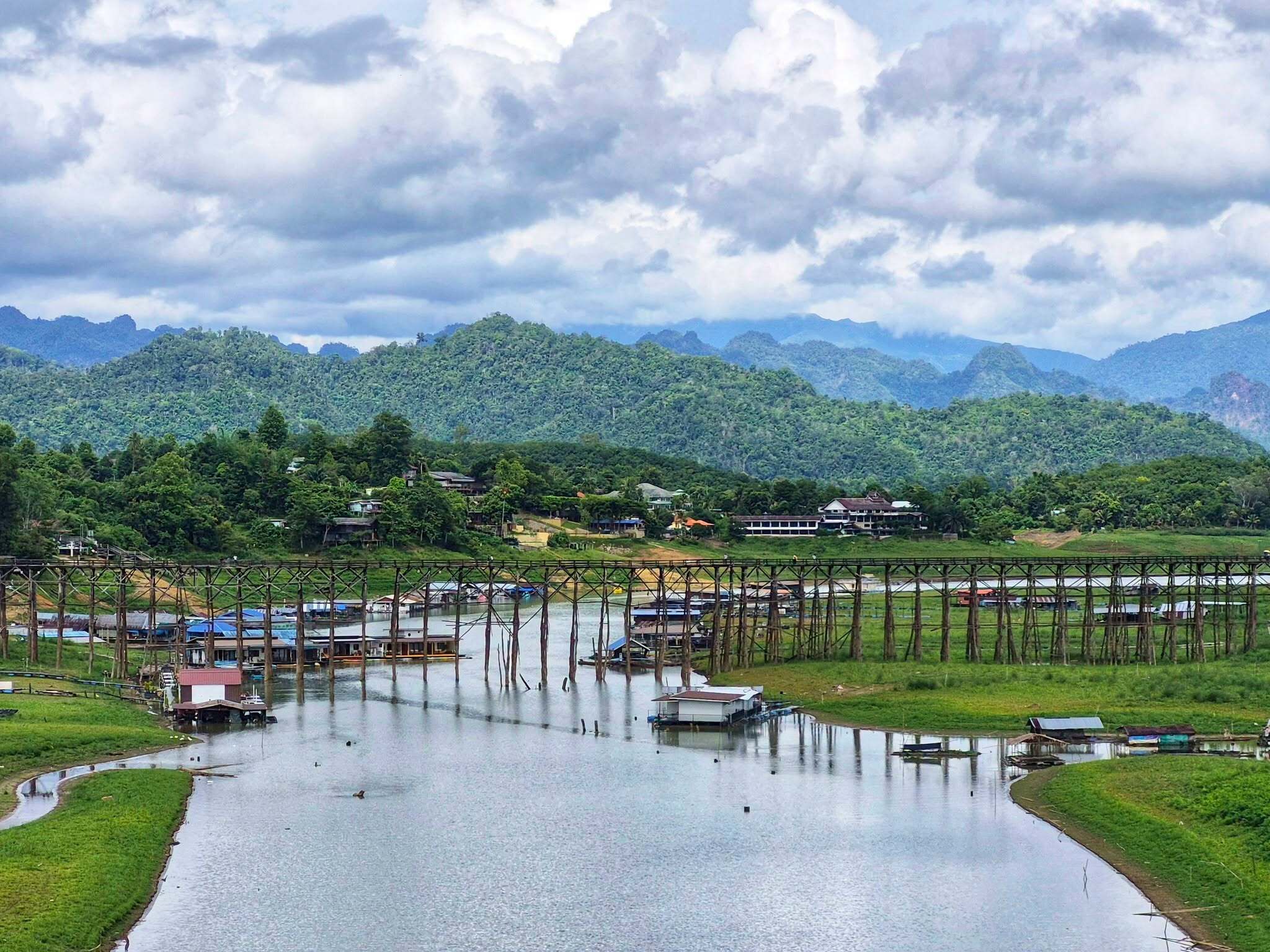A river with boats, a bridge, and houses on a hillside.