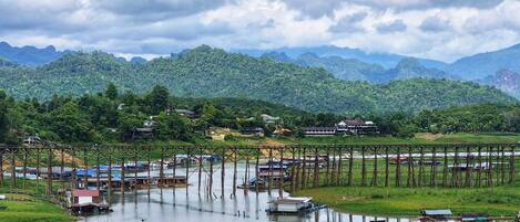 A river with boats, a bridge, and houses on a hillside.