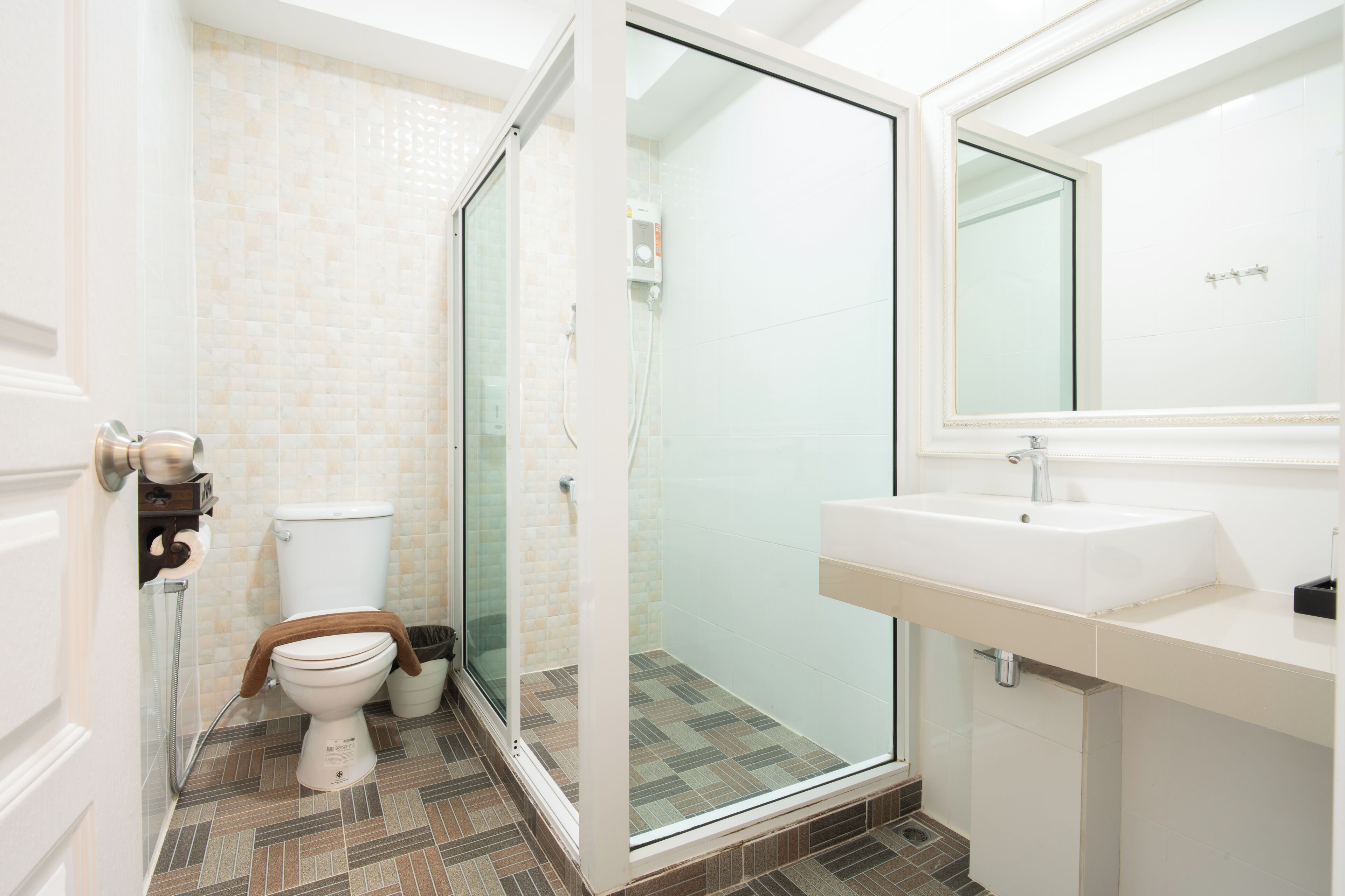 A modern bathroom with a glass-enclosed shower, a toilet with a towel, and a sink with a mirror.