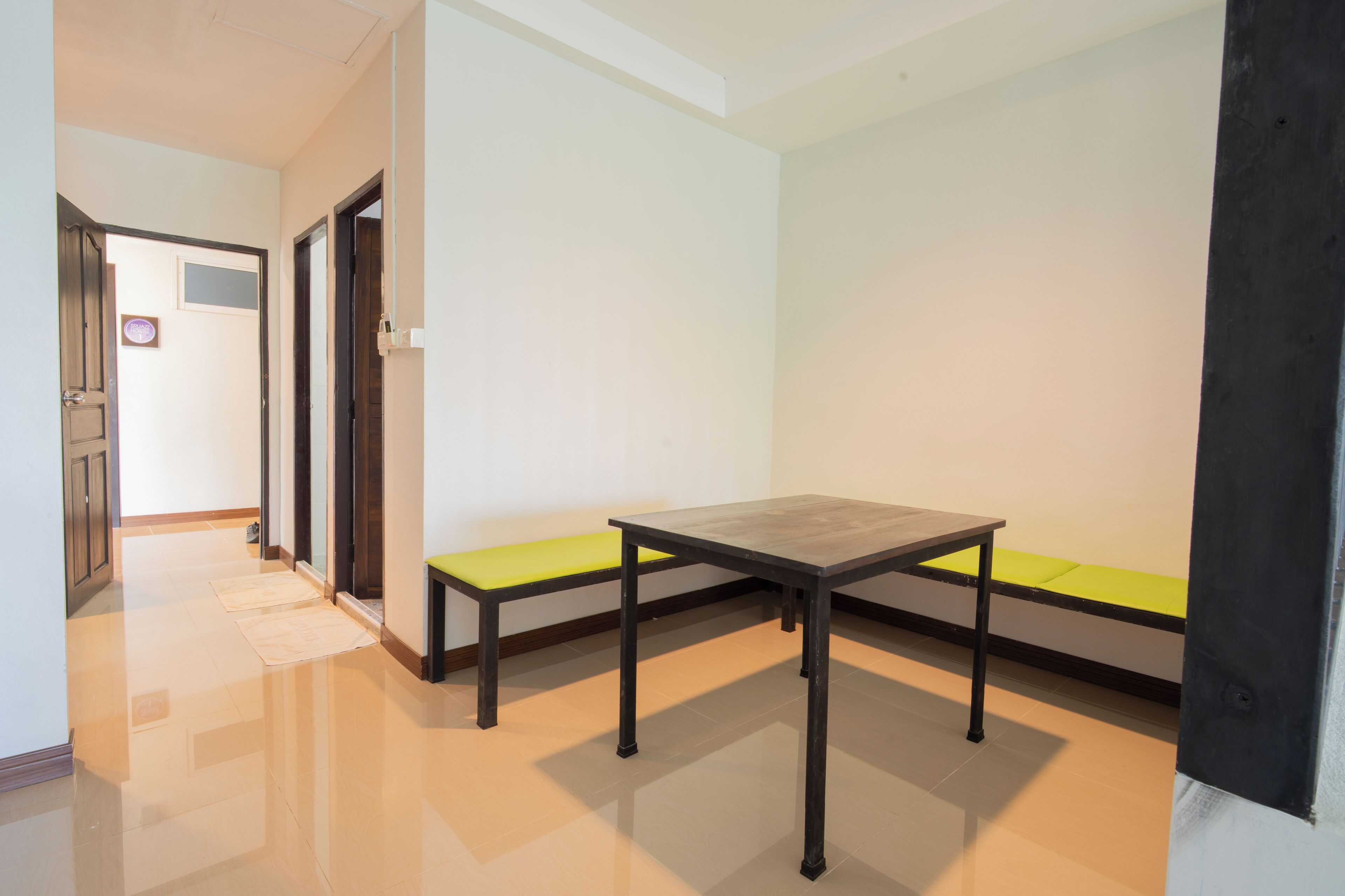 A room with a wooden table and a bench with a green cushion.