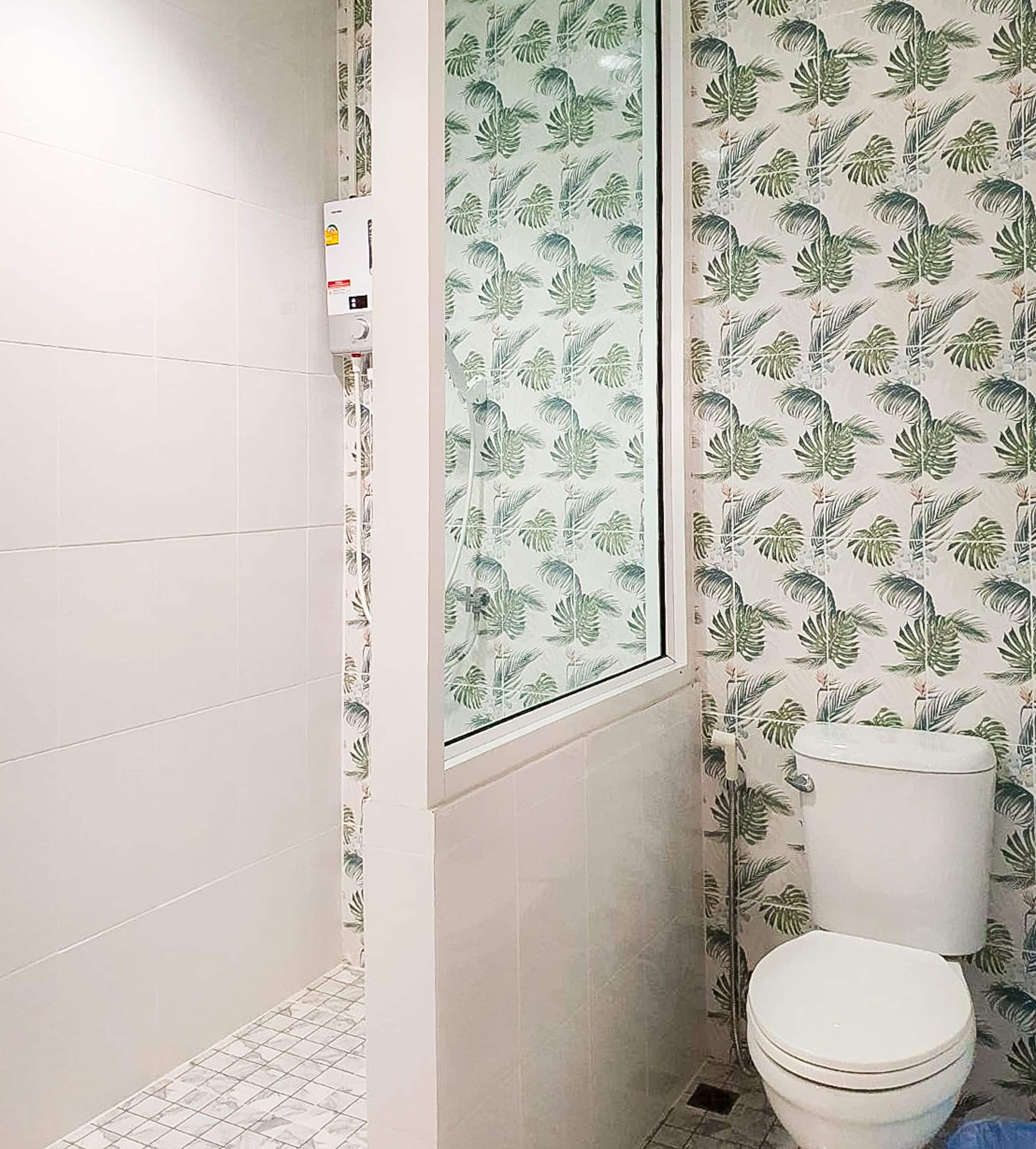 Een kleine badkamer met toilet, douche en raam.