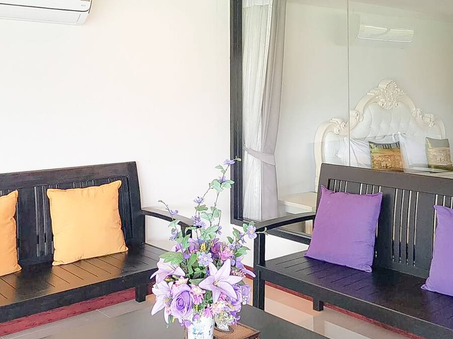 Um quarto com duas sofás de cor escura, cada uma com uma almofada, e uma mesa com um vaso de flores ao centro.