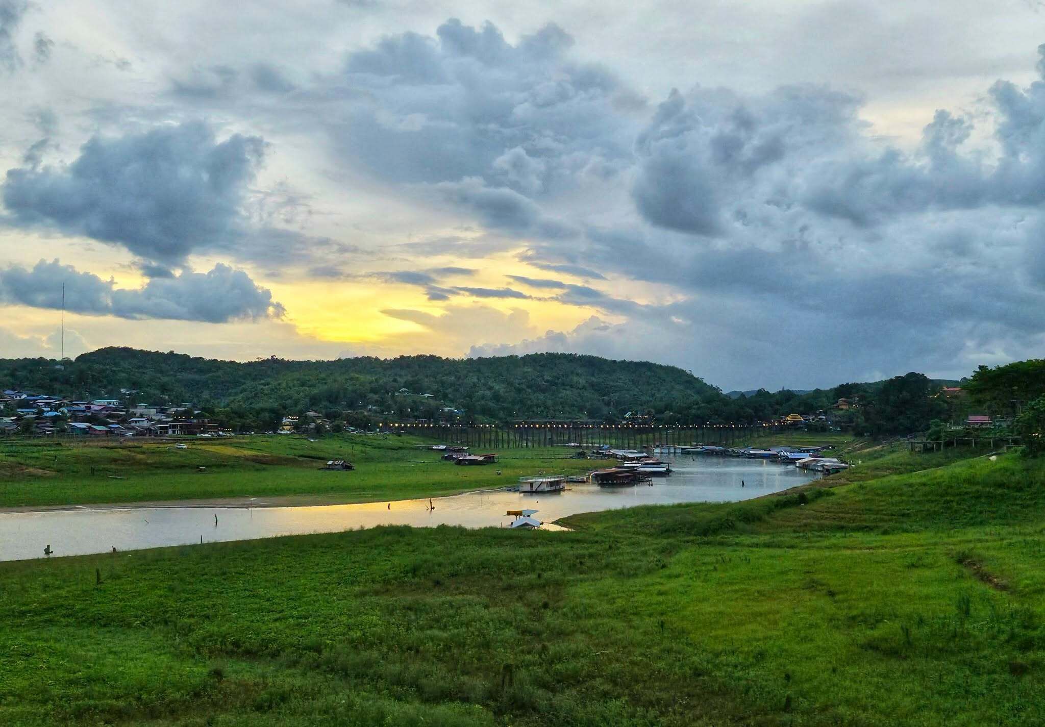 A river with boats, a bridge, and a hilly landscape with buildings.