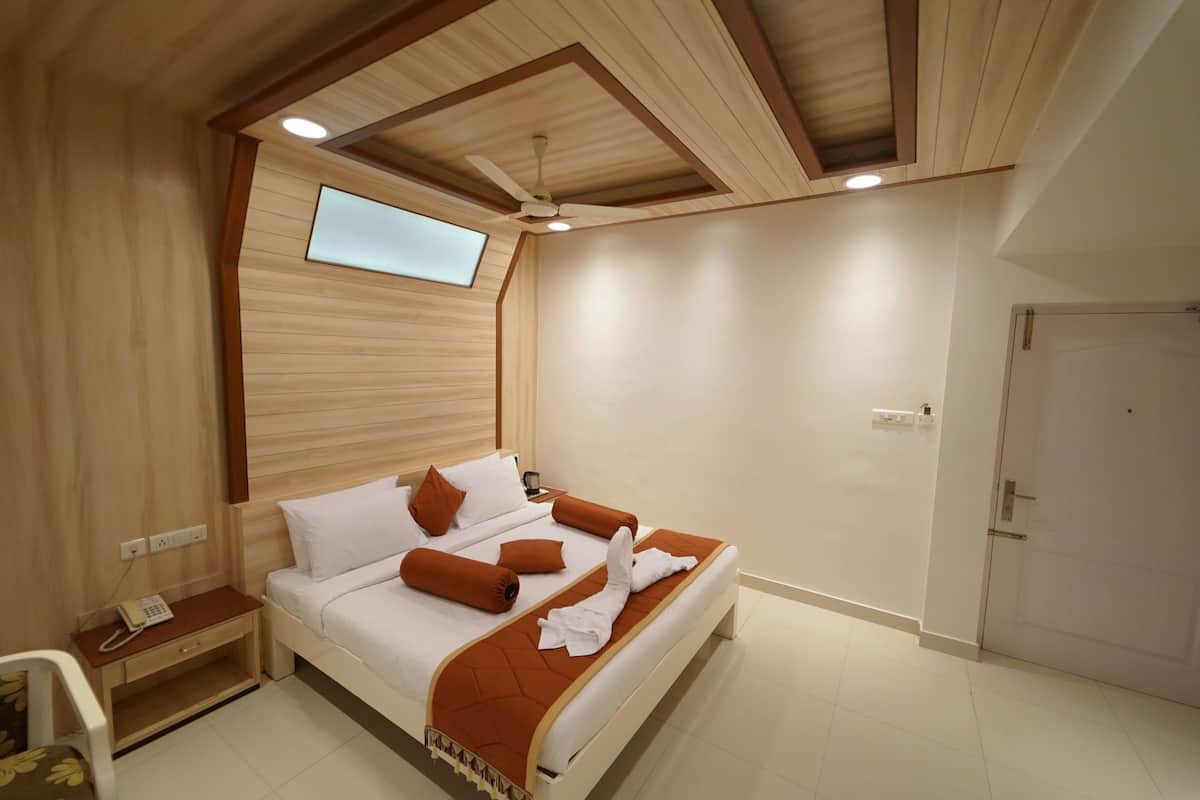 A hotel room with a bed, a desk, a telephone, a ceiling fan, and a door.