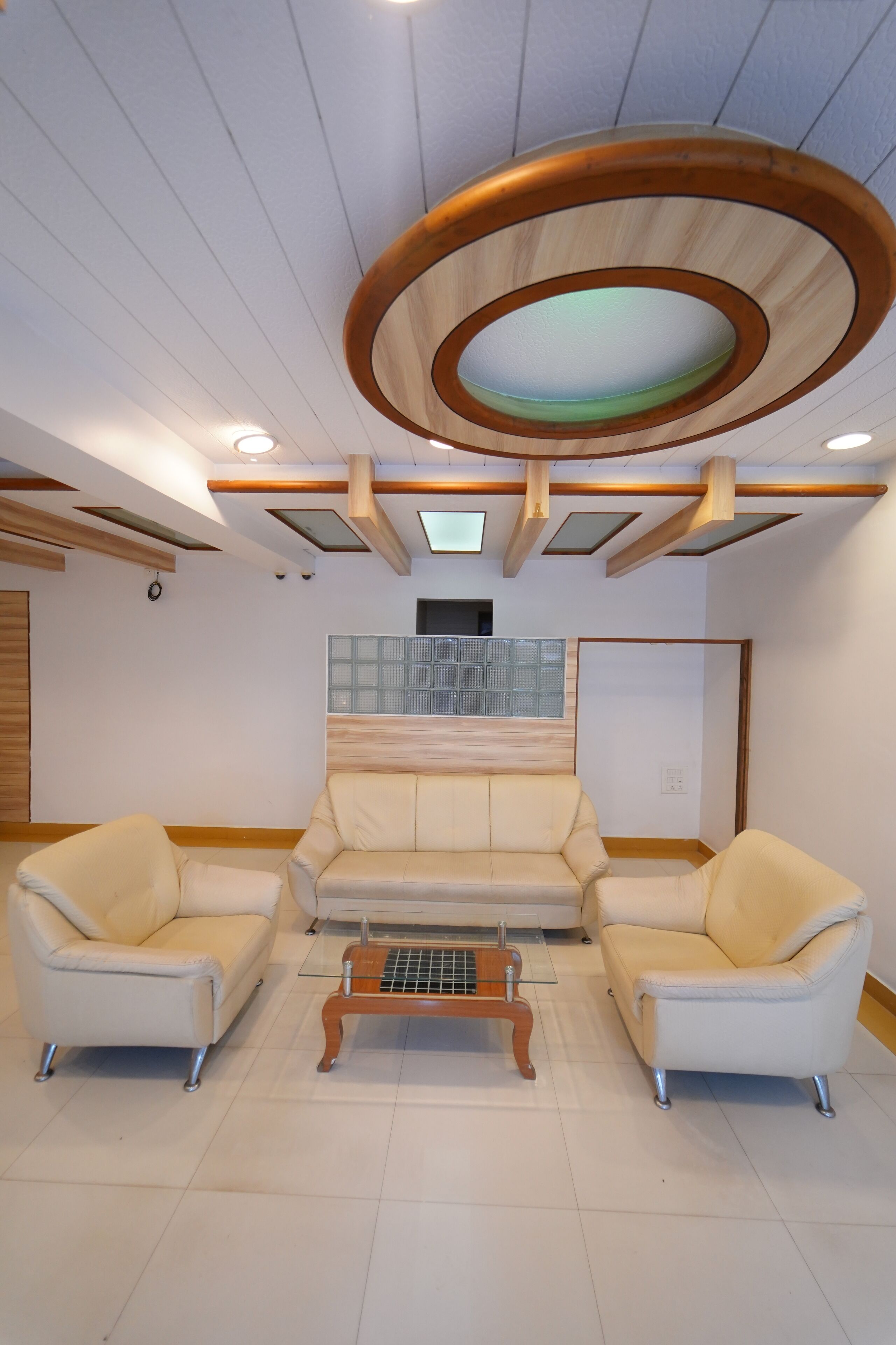A modern living room with a sofa set, a coffee table, and a unique circular ceiling design.