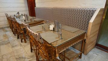 Une longue table à manger entourée de chaises, un mur orné de motifs et un sol en marbre.