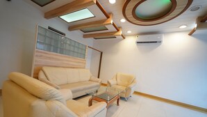 A modern living room with a sofa, armchair, and coffee table. - Hotel Palmyra Grand Inn (Tirunelveli)