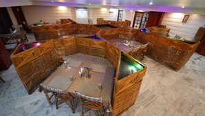 A restaurant with multiple seating areas, each with a table and chairs, and a bar area with a pool table. - Hotel Palmyra Grand Inn (Tirunelveli)