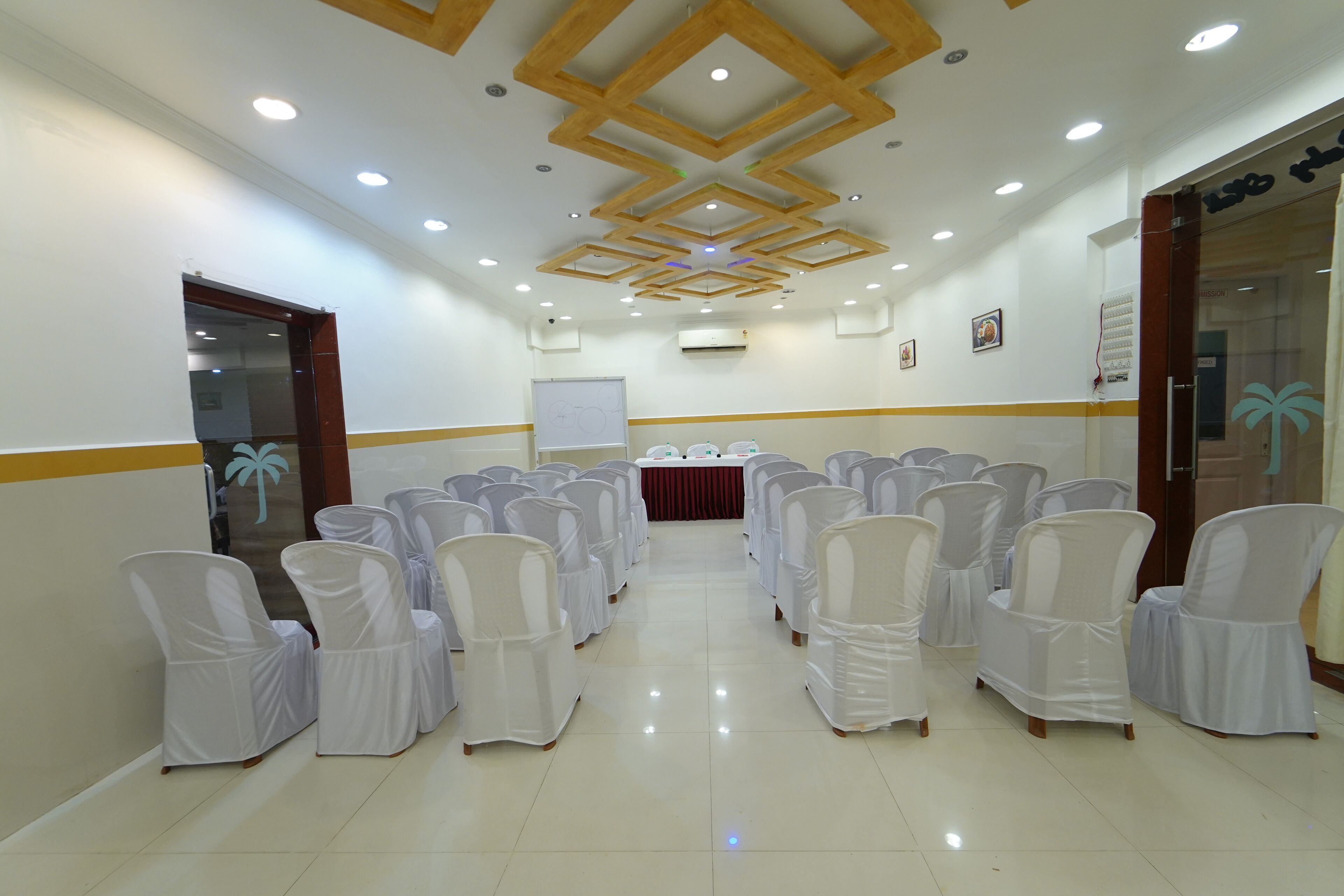 A conference room with rows of white chairs, a whiteboard, and a table with water bottles.