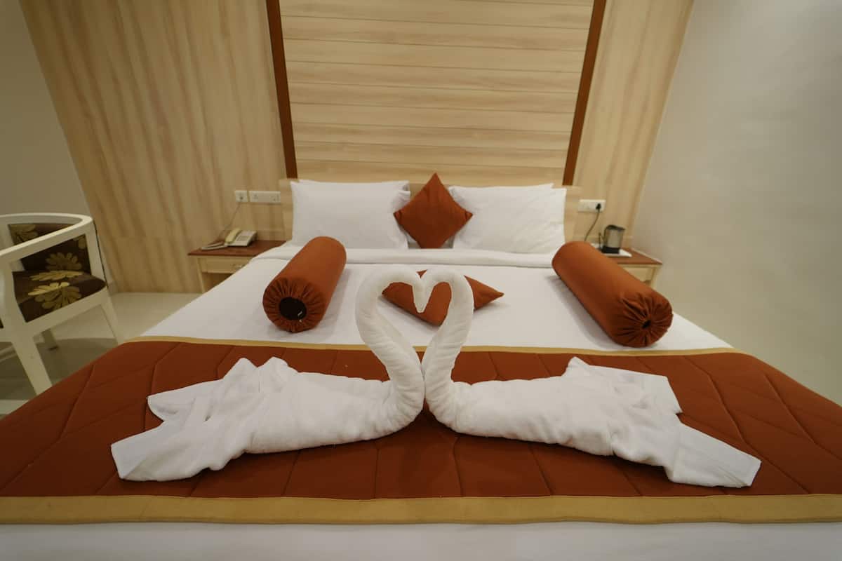 A hotel room with a neatly made bed, a bedside table with a phone, and a lamp.