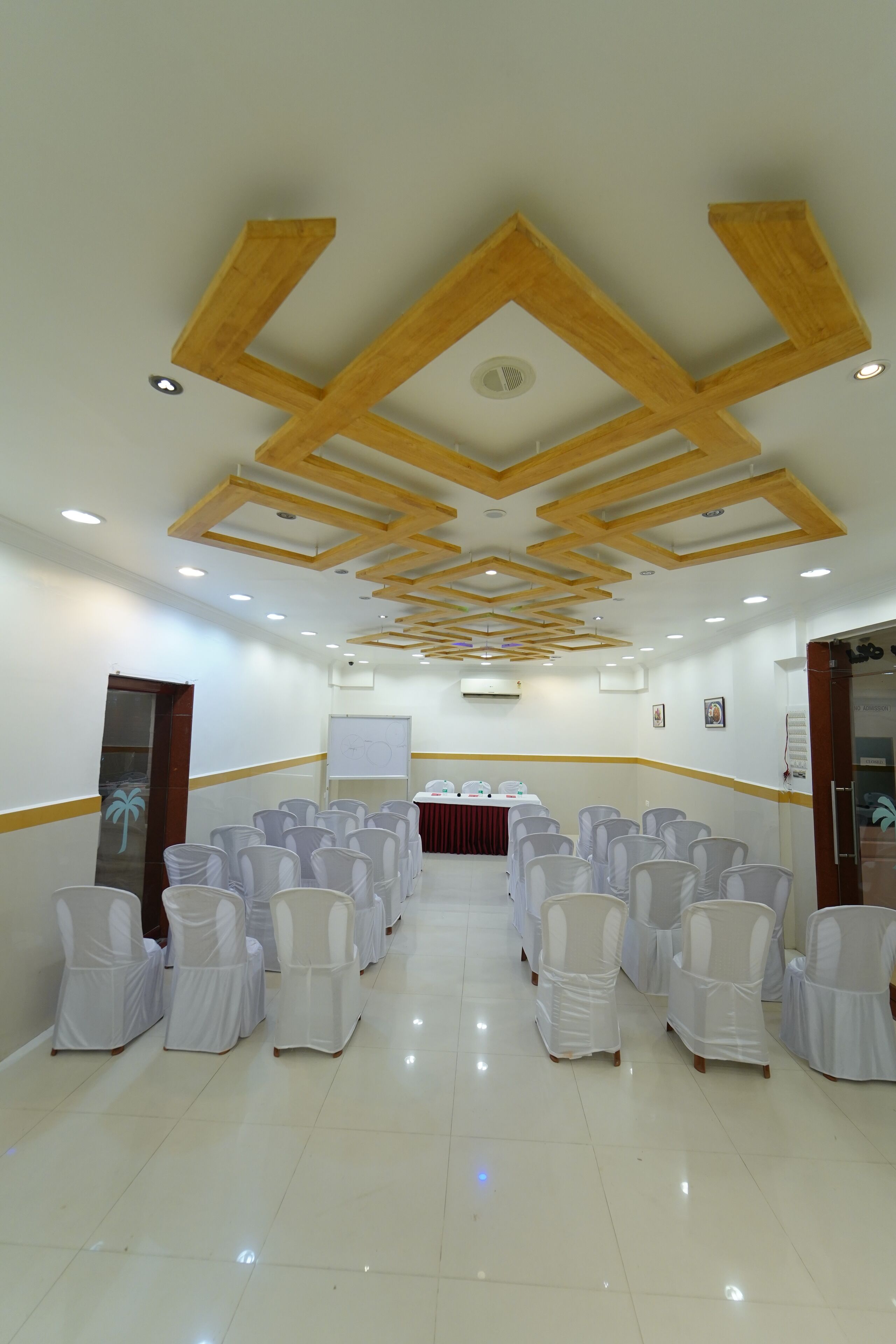 Una sala de conferències amb cadires blanques, una pissarra i bigues de fusta al sostre.