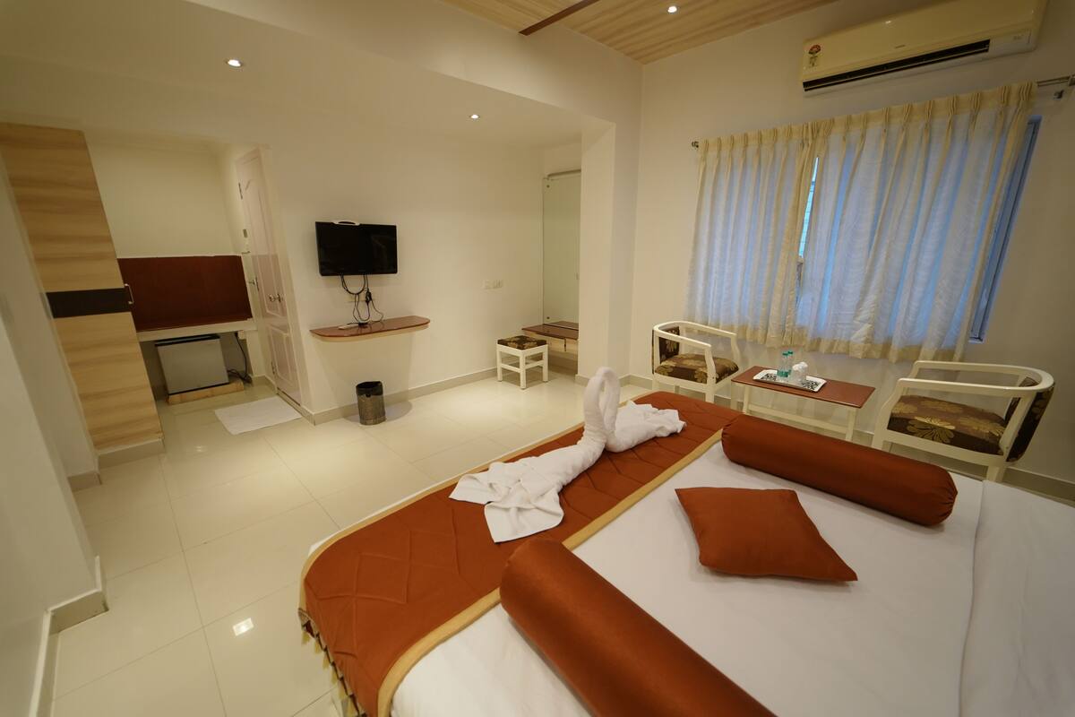 A hotel room with a bed, a TV, a desk, and a chair.