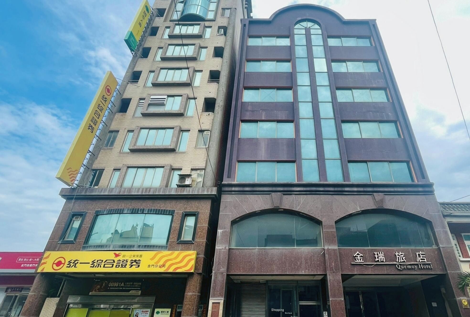 A multi-story building with a prominent entrance and signage for a hotel and a business establishment.