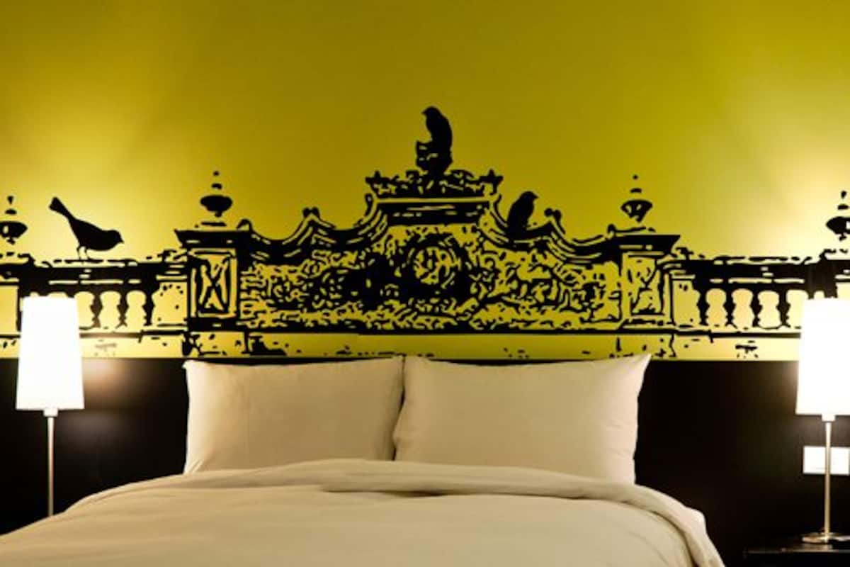 Ein Hotelzimmer mit Bett, zwei Nachttischlampen und einem dekorativen Wandbild.