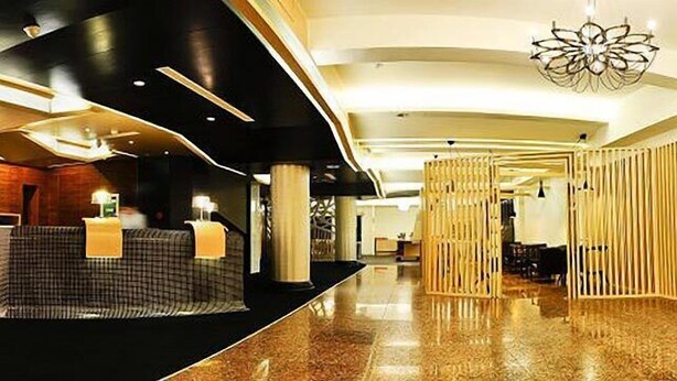 Eine moderne Hotelhalle mit Empfangstresen, einer Sitzecke und einer dekorativen Leuchte.
