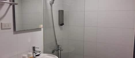 A bathroom with a white sink, mirror, and shower.