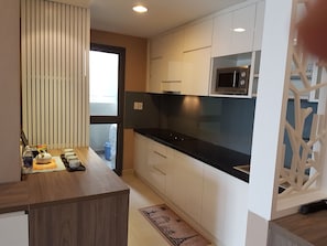 Kitchen features a sleek countertop, white cabinetry, and a microwave.