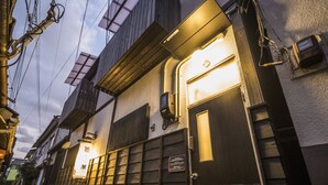 A traditional Japanese building with a wooden door, a small window, and a sign with Japanese characters. - Kyo Oyado Hana (Kyoto)