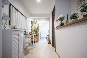 En gang med et hvidt skab, et bord med stole og en reol med planter.