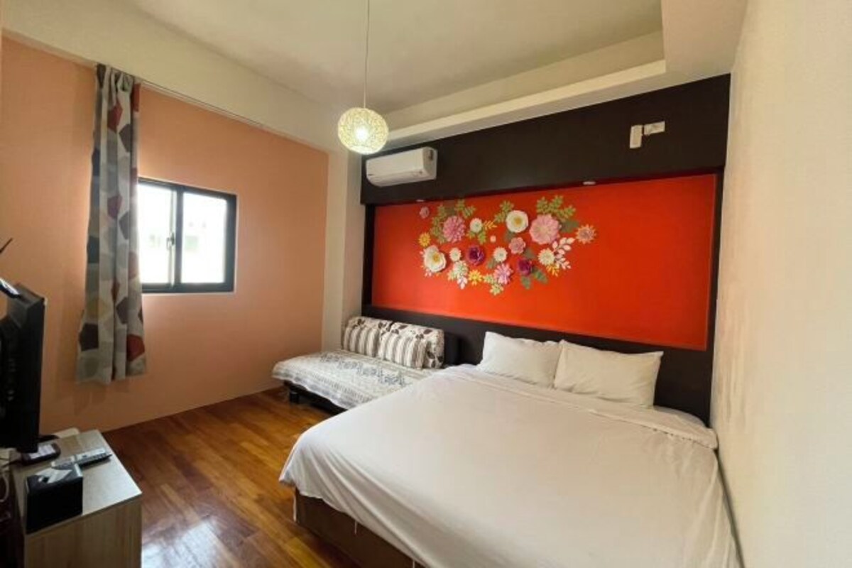 A bedroom with two beds, a TV, and a window with curtains.