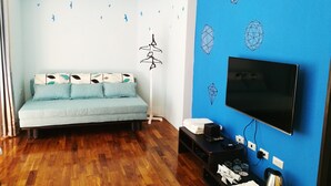 A modern living room with a light blue sofa, a flat-screen TV, and a wooden floor. - 198 Red Hat B&B (Magong)