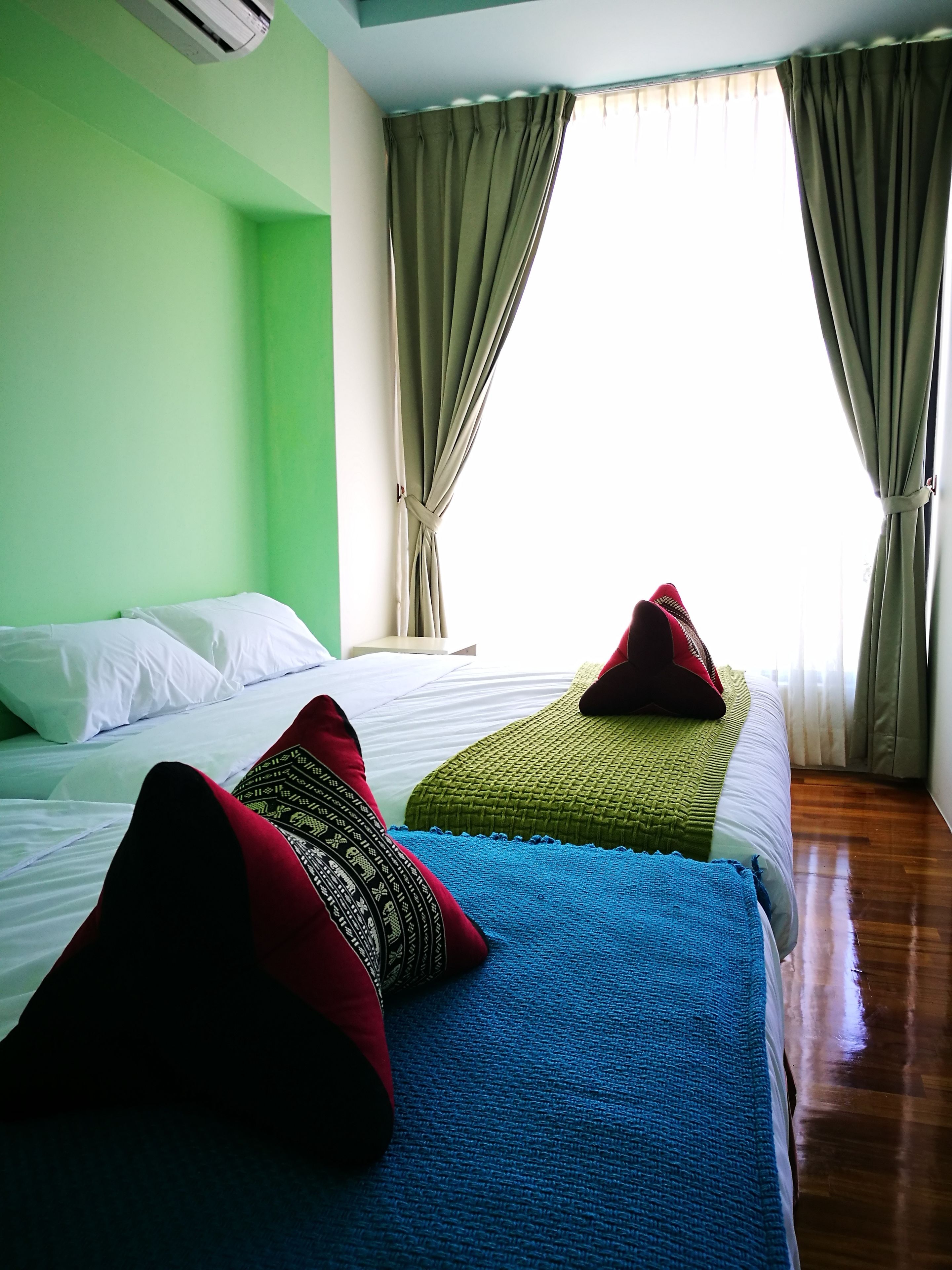 A hotel room with two beds, green walls, and curtains.