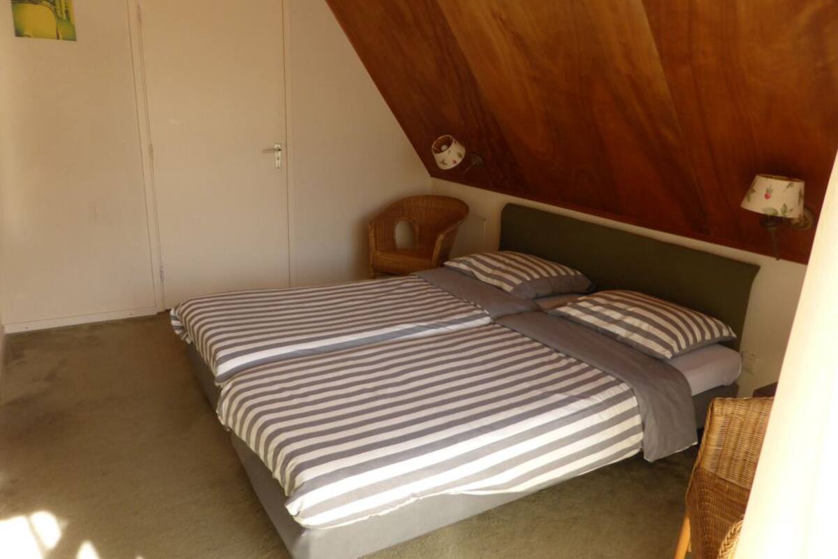 Ein Schlafzimmer mit einem Bett, einem Sessel und einer Lampe.