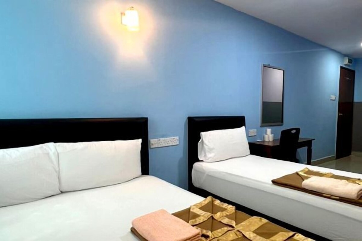 Una habitación de hotel con dos camas, un escritorio y un espejo.
