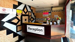 Een receptiebalie met een bordje 'Reception', een 'Niet roken'-bord en nog een 'Reception'-bord aan de muur.