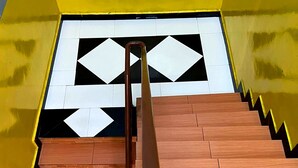 Een trap met houten treden en een zwart-wit geometrisch patroon op de muur.
