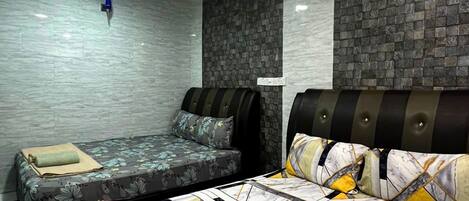 Quarto de hotel com duas camas, parede revestida de azulejos e luminária no teto.