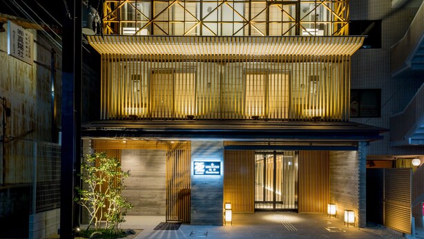 A two-story building with a modern design, featuring a wooden facade and a balcony with vertical slats. - RESI STAY Kumico Amaterrace (Kyoto)