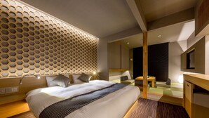 A modern hotel room with a large bed, a wooden headboard, a seating area with a table, and a large mirror. - RESI STAY Kumico Amaterrace (Kyoto)