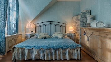 A bedroom with a bed, two bedside tables, a nightstand, a wooden cabinet, and a window with curtains.