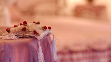 A bed with a pink bedspread and a decorative pillow with red roses.
