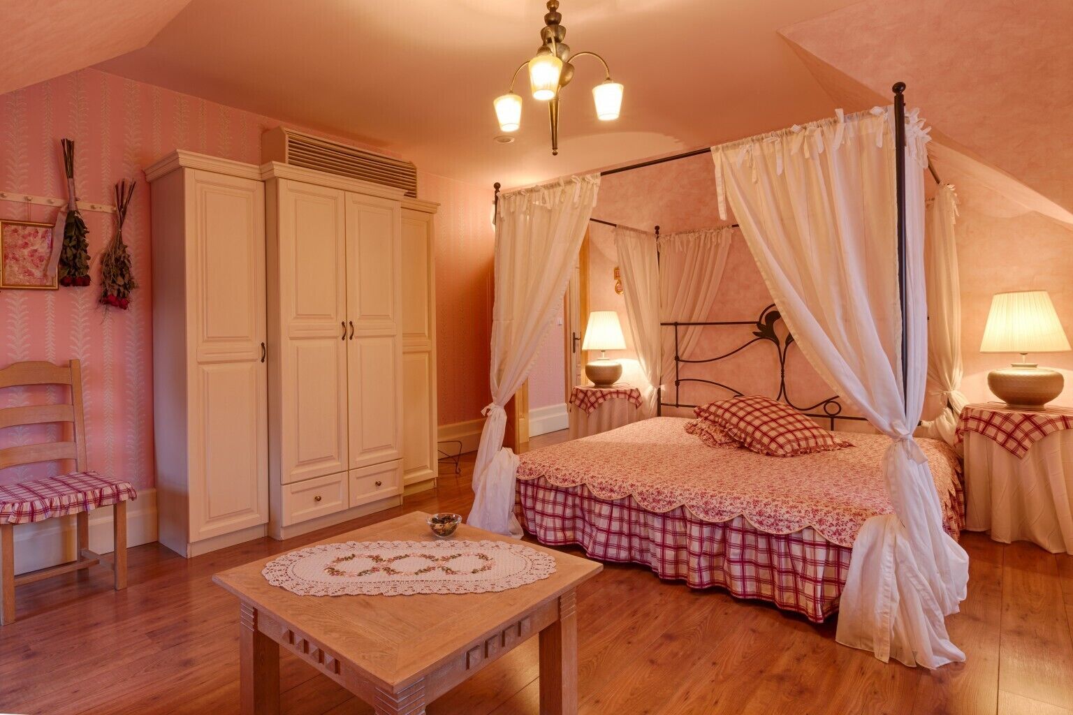 A bedroom with a four-poster bed, a wooden nightstand, a chair, and a wardrobe.