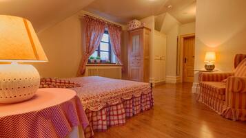Ein gemütliches Schlafzimmer mit Bett, Nachttisch mit Lampe, Fenster mit Vorhängen, Heizkörper, Holztür und einem gestreiften Sessel.