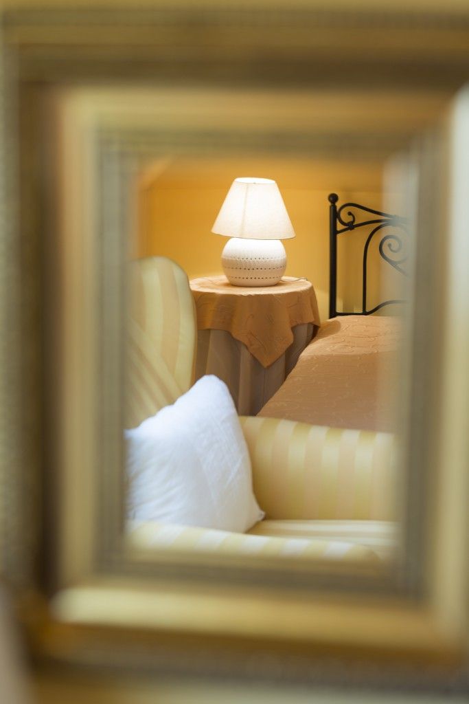 Een kamer met een bed, een nachtkastje met een lamp en een stoel, in een lijst.