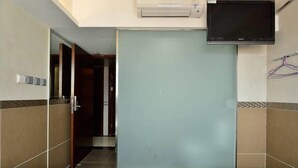 Habitación de hotel con dos camas, un televisor montado en la pared y una puerta corredera que da a un pasillo.